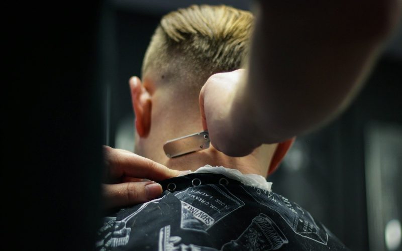 person trimming man's hair