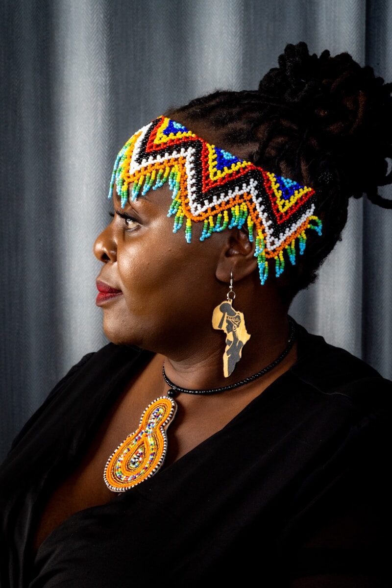 Woman wearing colorful beaded headband and african pendant.